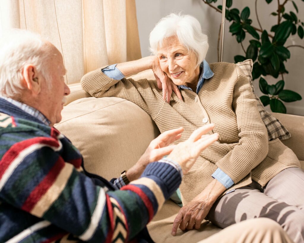 Ritratto di una dolce coppia di anziani che conversa seduta sul divano a casa.